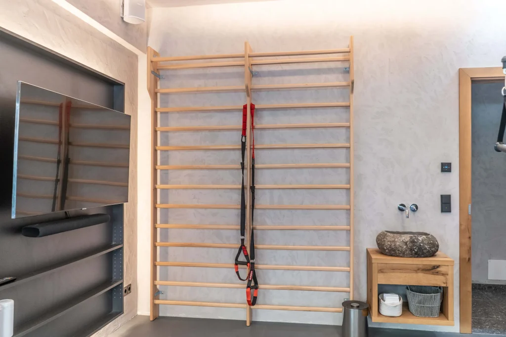 Hölzerne Sprossenwand mit Sling-Trainer in einem modernen Fitnessraum.