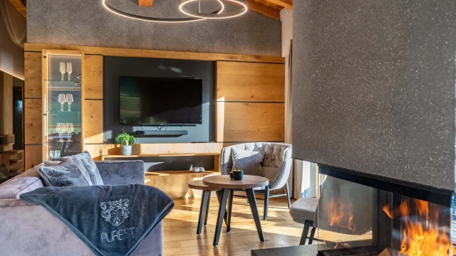 Modernes Wohnzimmer mit Kamin, Fernseher und gemütlichem Sofa.