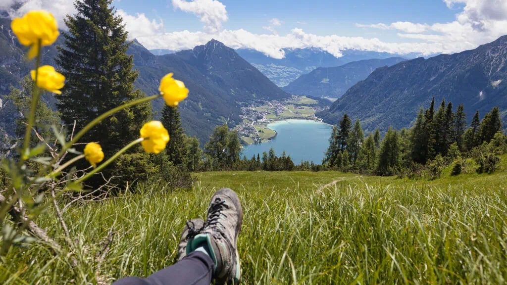 Blick von einer Bergwiese auf einen See in den Alpen.