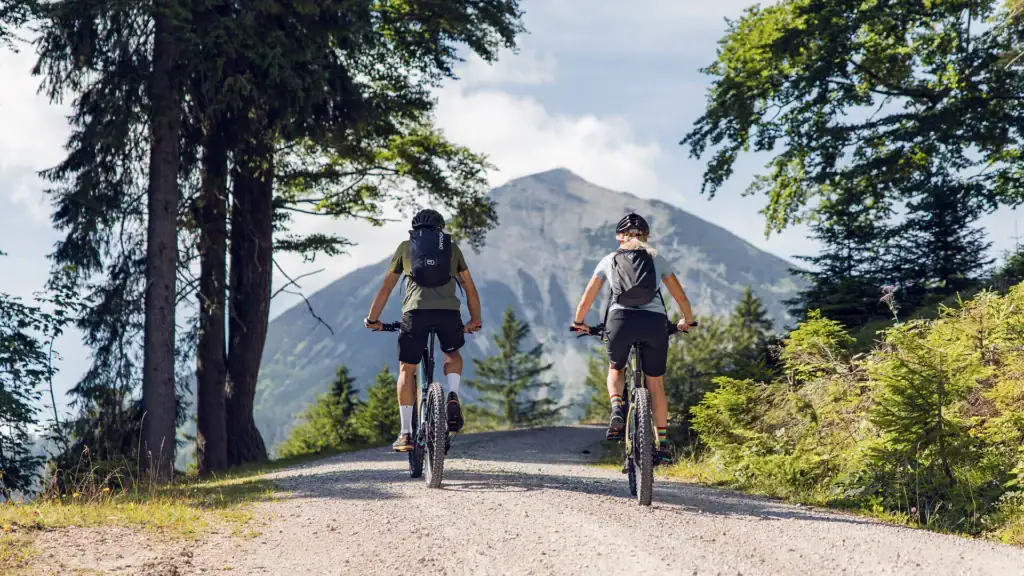 Zwei Radfahrer auf Bergpfad mit Blick auf Achensee und Berge.